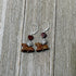 Handcrafted Jasper Horse Earrings with silver hooks feature a red-brown heart bead, silver spiral bead, and dog-shaped brown stone. Displayed on weathered wood—perfect Spring Equestrian Jewelry Gift for horse lovers.