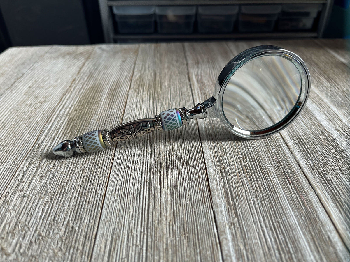 Close-up of Eye Catching Gift - Shimmering Bead Handed Magnifier showcasing its 2-inch lens and artistic design, ideal office crafting tool.
