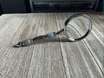 Close-up of Eye Catching Gift - Shimmering Bead Handed Magnifier showcasing its 2-inch lens and artistic design, ideal office crafting tool.