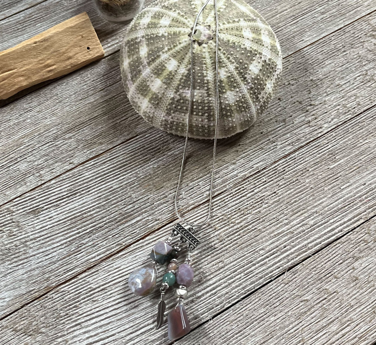 Close up of Fancy Jasper Triple Charm Pendant Necklace, decorated with feather and colorful Jasper stones for spirituality.