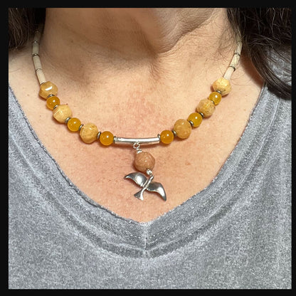 Close-up view of the Silver Bird in Flight Necklace showcasing vibrant orange and yellow stones and sterling silver bird charm.