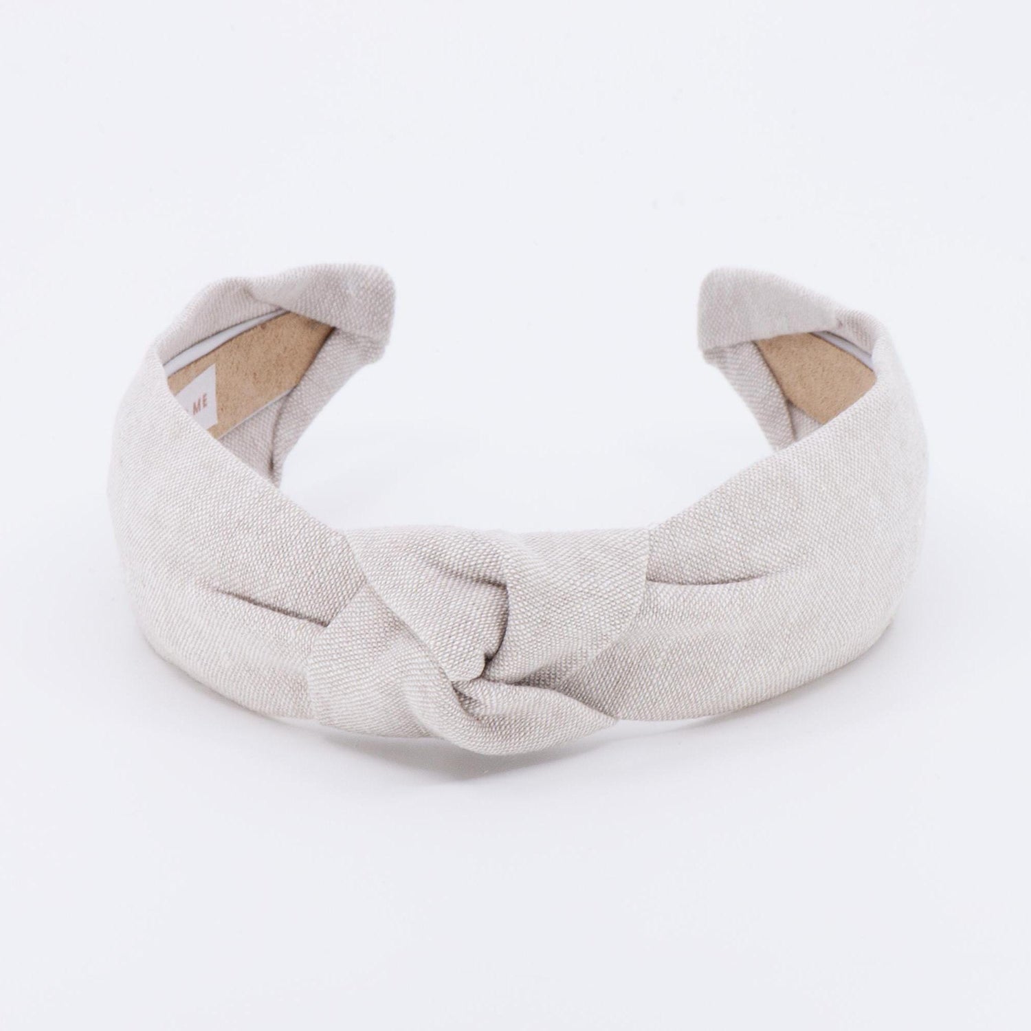 A light tan knotted headband made of linen fabric.