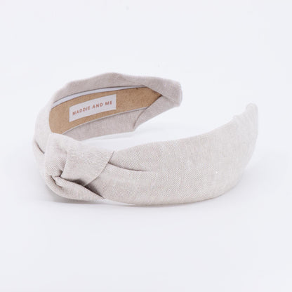 A light tan knotted headband made of linen fabric. The headband has a label that says &amp;quot;MADDIE AND ME&amp;quot;.