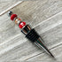 The Handcrafted Red Beaded Wine Stopper – Unique Hostess Gift features shiny silver, gold, and red beads on a metallic handle with black rubber rings—an elegant artisan wine accessory displayed on light wood.