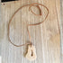 The Adjustable Leather Necklace with Stone Pendant: Minimalist Earthy Jewelry features a natural, uniquely shaped stone on an adjustable leather cord, presented on rustic wood—a striking piece of minimalist style.