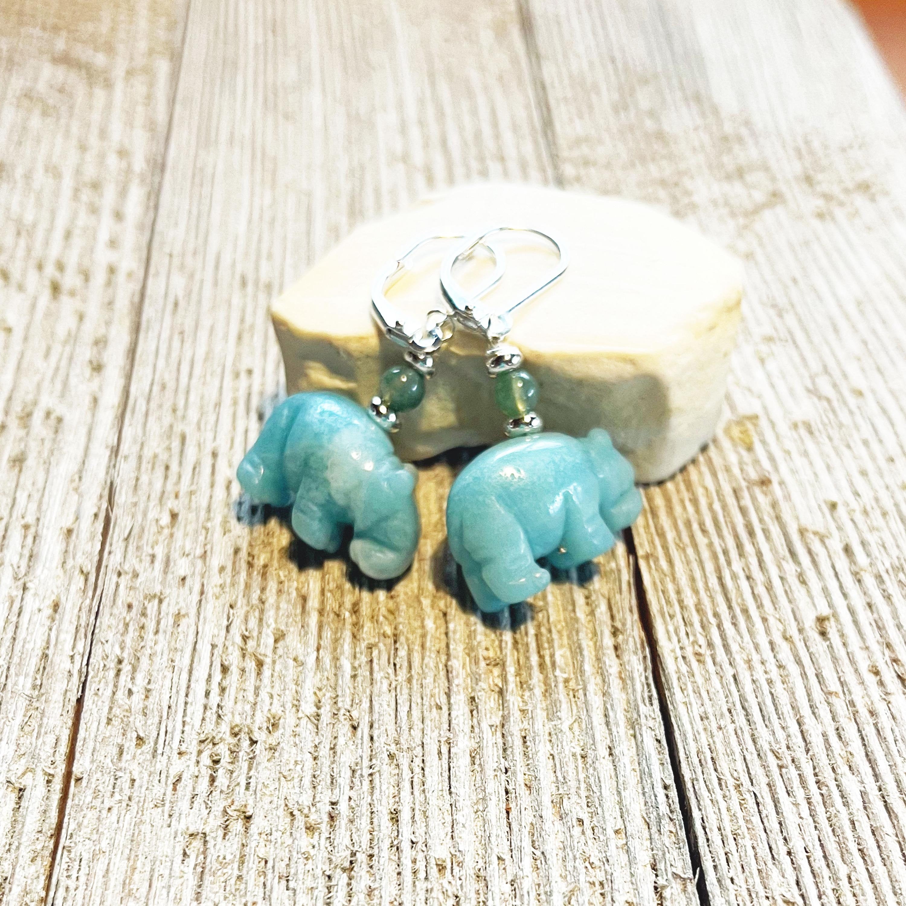 Serene Sky Blue Aventurine Hippo Earrings with Jasper beads—handcrafted for animal lovers. These unique earrings, featuring hippo accents and green jasper, make a perfect gift and are displayed on a weathered wooden surface.