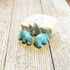 Serene Sky Blue Aventurine Hippo Earrings with Jasper beads—handcrafted for animal lovers. These unique earrings, featuring hippo accents and green jasper, make a perfect gift and are displayed on a weathered wooden surface.
