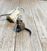 A Handmade Porcelain Quagga Figurine Bookmark with a metal key ring rests on textured wood, making a unique animal lover gift for book lovers.