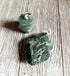 The Chunky Style Masc Forest Green Stone Pendant—an earthy gemstone on a 5mm cord with a silver bail—rests on rustic, light wood, showcasing its forest green color and marbled finish for an eye-catching natural necklace.