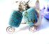 Turquoise Howlite Earrings: Thai Silver Swirl Dangle feature rectangular blue stones with dark veins, silver beads, and spiral charms. Artisan designed jewelry, displayed on a white and light purple background.