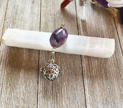 The Handcrafted Zen Aromatherapy Chamber features a large purple agate stone and a round, detailed Namaste symbol, presented on a white crystal base atop a wooden surface.