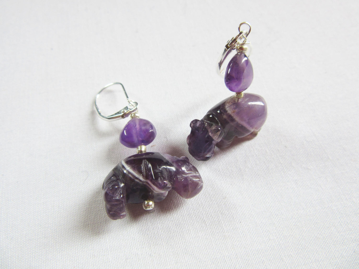 Handcrafted Amethyst Hippo Earrings with Sterling Silver lever backs, featuring carved purple hippos and round amethyst beads—ideal for lovers of unique handmade jewelry and displayed on a white background.