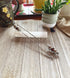 Two Purple Faceted Glass Beaded Drink Stir Sticks—elegant cocktail decor—rest on a white crystal atop wood. In the background are a ceramic cup, potted plant, and other decor. Set of 2.