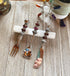 The Purple Beaded Utensil Set—elegant appetizer fork, spoon, and knife—rests on a white crystal holder on wood, complemented by a decorative turtle and potted plant for an elegant entertaining scene.