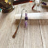 The Amethyst Bookmark: Artisan Designed Divine Goddess Celestial Gift features engraved metal, purple beads, and an amethyst angel charm, pictured on a white selenite stick—making it a perfect celestial-themed present.