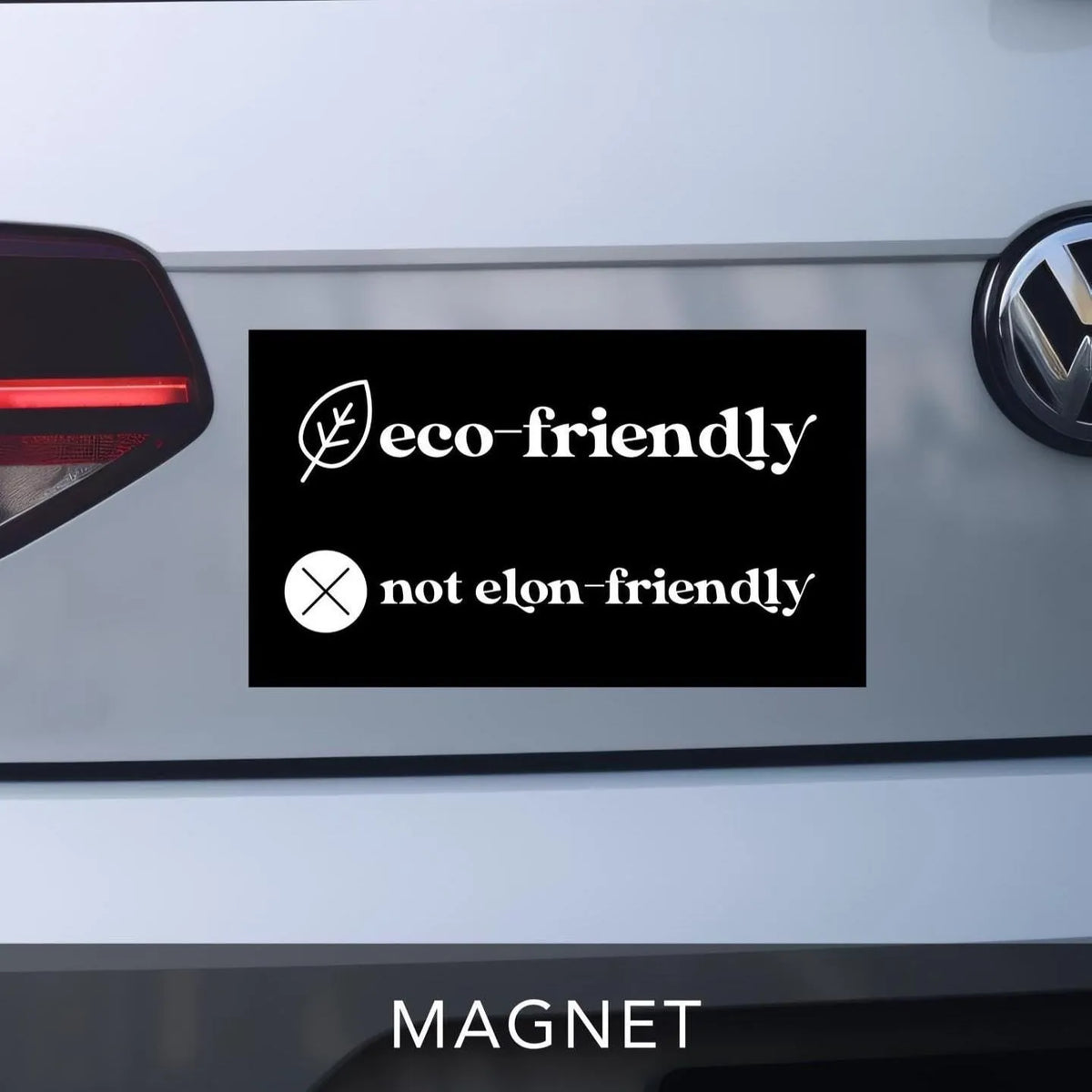 car bumper magnet in black and white reads &amp;quot;eco-friendly&amp;quot; with leaf graphic on top line.  Bottom line reads &amp;quot;not elon-friendly&amp;quot; with X graphic next to it.  Anti-Elon Musk Bumper Sticker