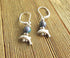 Handcrafted Dolphin Earrings feature small silver dolphin charms and dark color changing mood beads, displayed on a slatted wooden surface—a unique boho ocean jewelry addition.