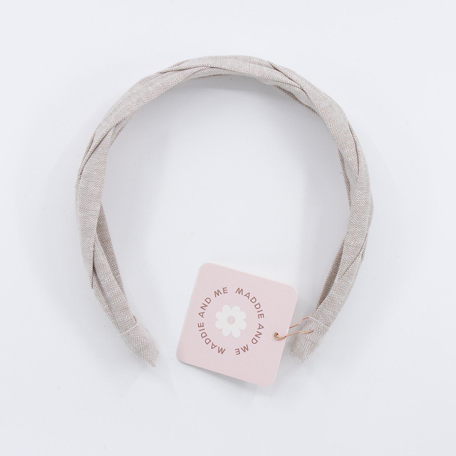 A light tan braided linen headband. The headband has a tag that says &amp;quot;MADDIE AND ME&amp;quot;.