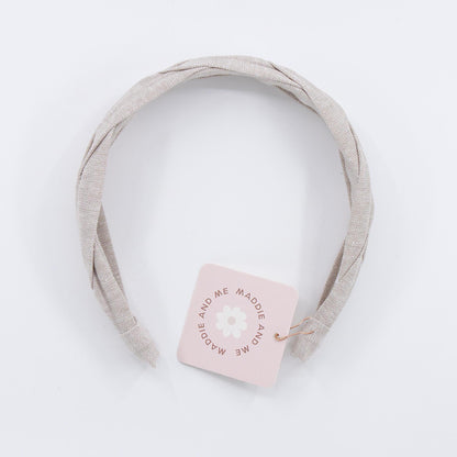 A light tan braided linen headband. The headband has a tag that says &amp;quot;MADDIE AND ME&amp;quot;.