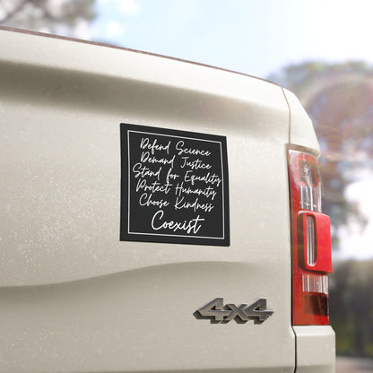 Square black bumper magnet with white handwritten font reading “Defend Science, Demand Justice, Stand for Equality, Protect Humanity, Choose Kindness, Coexist&amp;quot;