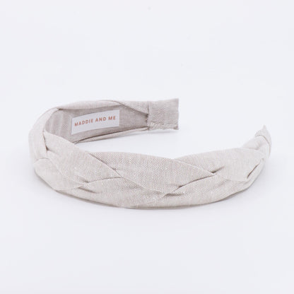 A light tan braided linen headband. The headband has a label that says &amp;quot;MADDIE AND ME&amp;quot;.