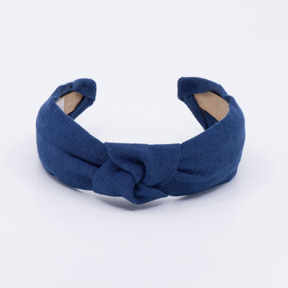 May include: A dark blue knotted headband made of fabric.