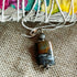 The Ocean Jasper Stormy Pendant—a rare natural stone necklace for winter minimalists—rests on textured burlap, radiating grounding energy. Its earthy tones and silver chain pair with a colorful bundle, enhancing the pendant’s organic charm.