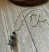 The Carved Obsidian Dog Necklace - Color Change Bead, Pet Memorial features a small dog pendant and a color-changing bead, displayed on a rustic wooden surface.