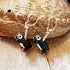 Handpainted Puffin Earrings—charming puffin bird charms on silver hooks—are displayed with a seashell and wood backdrop, making a perfect marine bird lover gift.