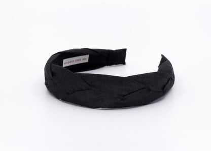 May include: A black braided headband made of fabric.