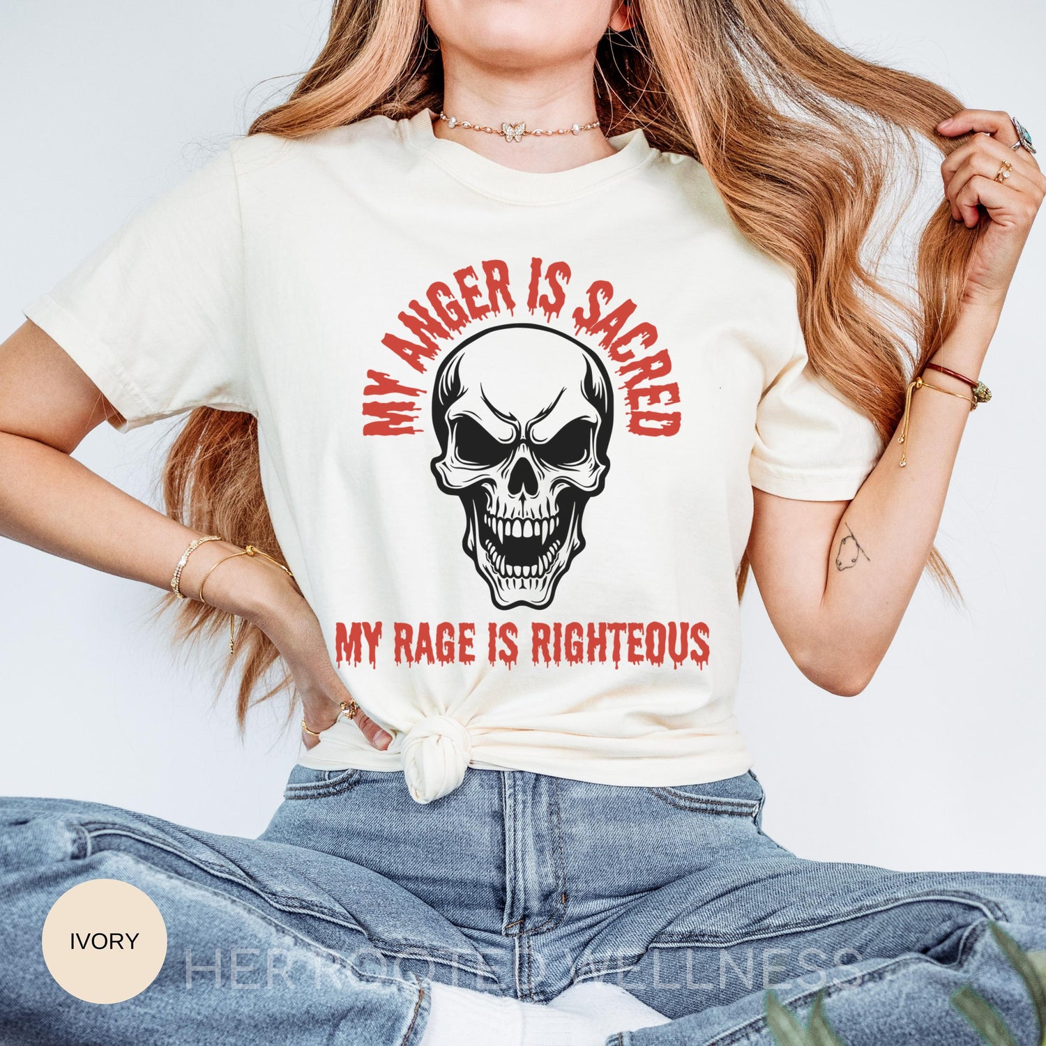 May include: Ivory-colored t-shirt with a skull graphic and the text &amp;quot;MY ANGER IS SACRED&amp;quot; and &amp;quot;MY RAGE IS RIGHTEOUS&amp;quot; in red. The skull has a menacing expression. The shirt is a casual wear item.