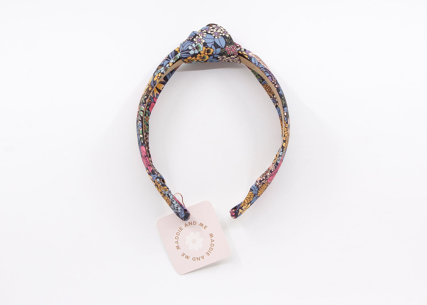 A floral print headband with a knotted design. The headband has a tag that says &amp;quot;MADDIE AND ME&amp;quot;.