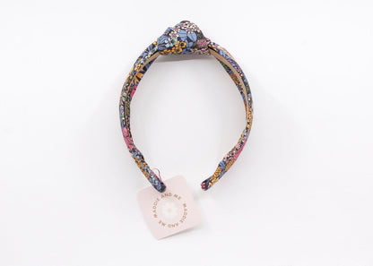 A floral print headband with a knotted design. The headband has a tag that says &amp;quot;MADDIE AND ME&amp;quot;.