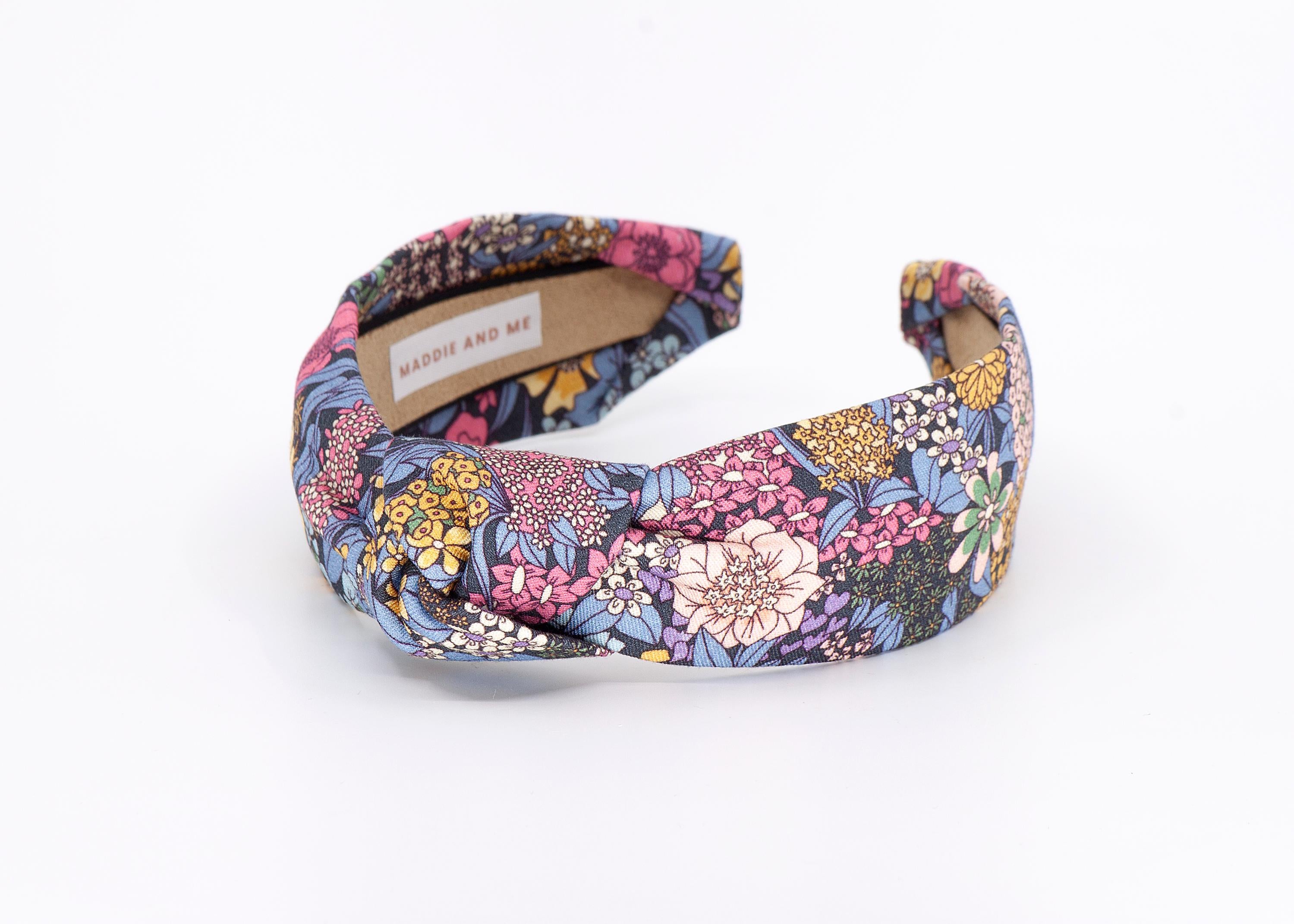 A floral print headband with a knotted design. The headband has a label that says &amp;quot;MADDIE AND ME&amp;quot;.