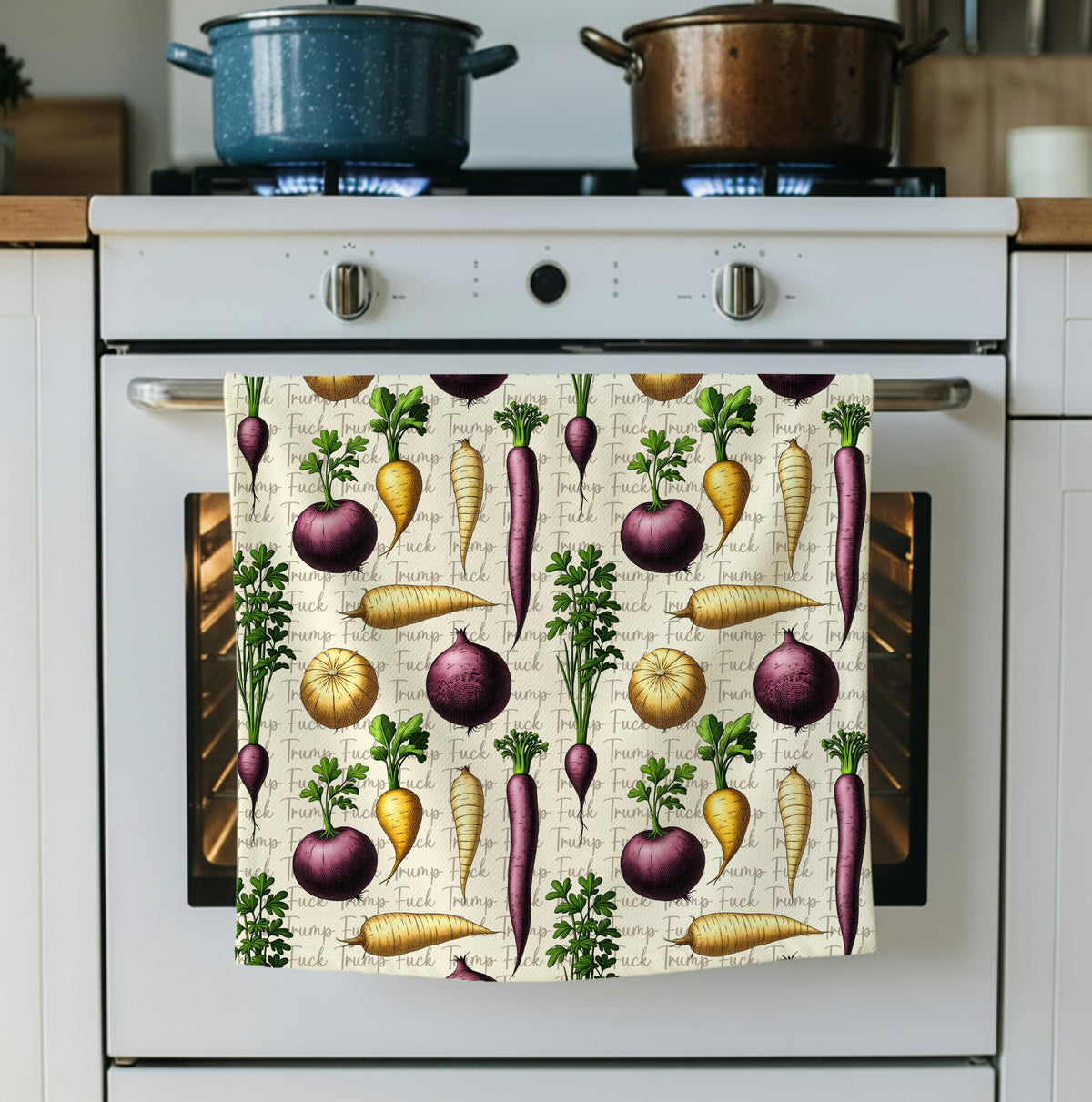 Towel with a pattern of carrots, radishes, and pumpkins on a stove.