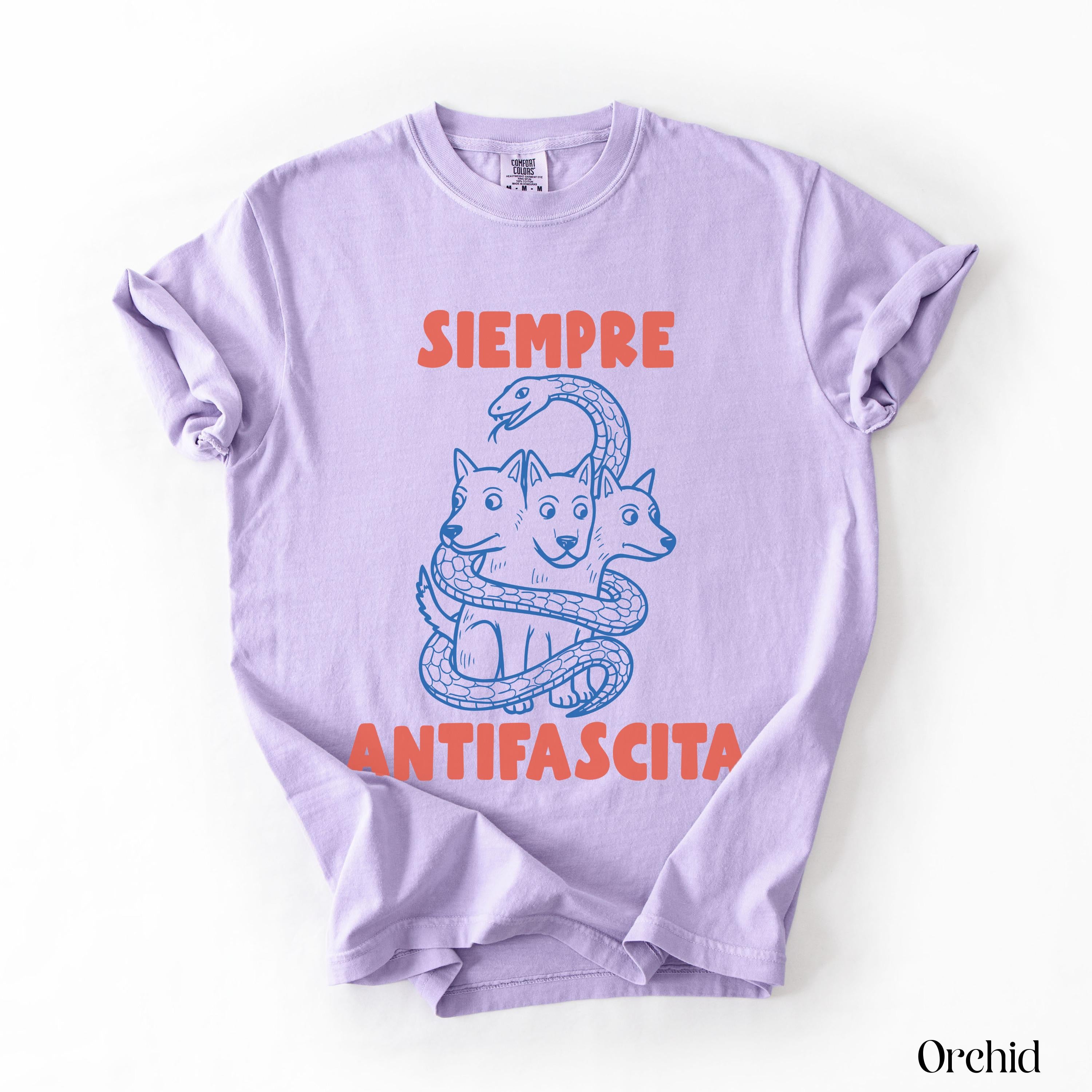 Lavender t-shirt with blue ink illustration of three-headed dog and text &amp;quot;SIEMPRE ANTIFASCISTA&amp;quot;.