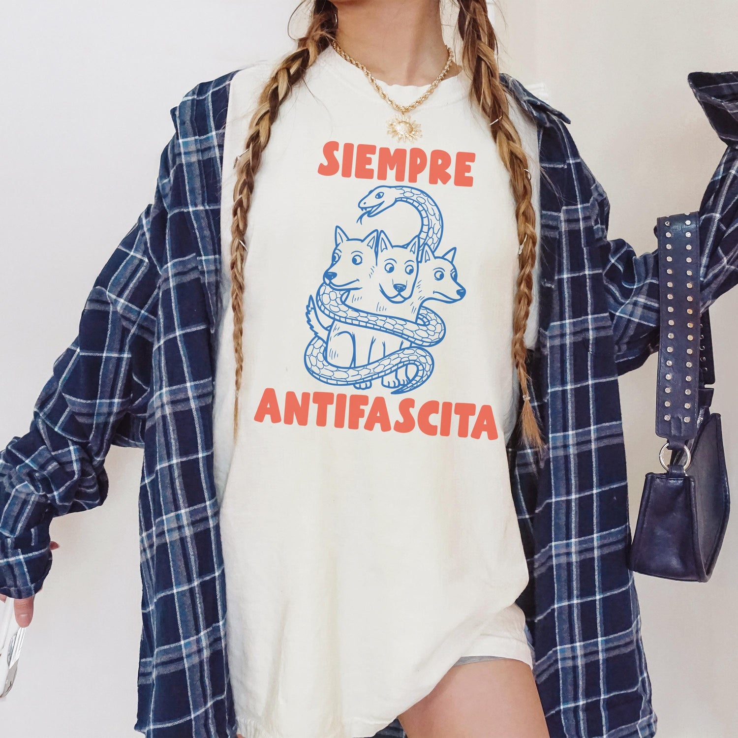 Cream t-shirt with red text &amp;quot;SIEMPRE ANTIFASCISTA&amp;quot; and three-headed dog graphic.