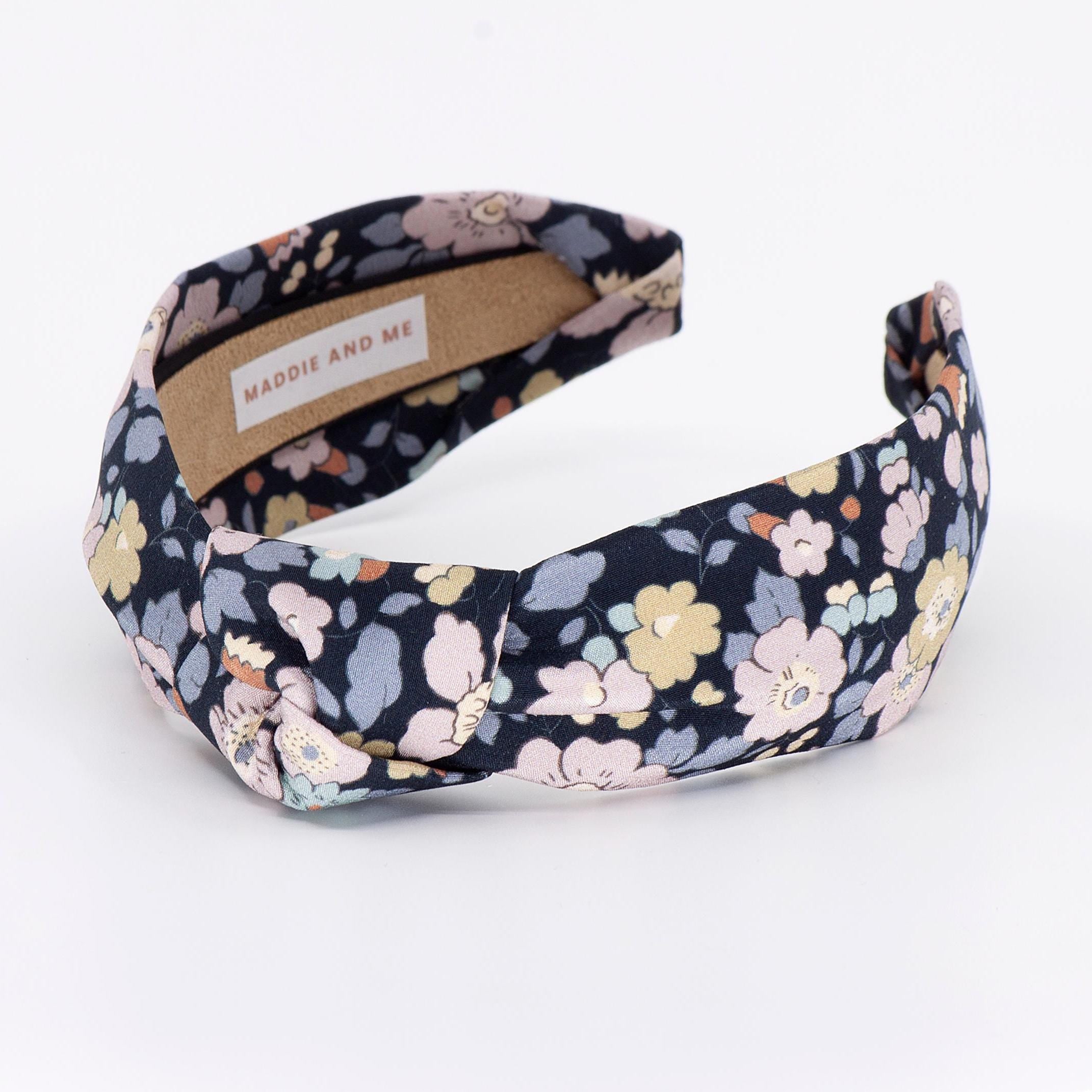 A floral-patterned headband with a knotted design. The headband has a label that says &amp;quot;MADDIE AND ME&amp;quot;.