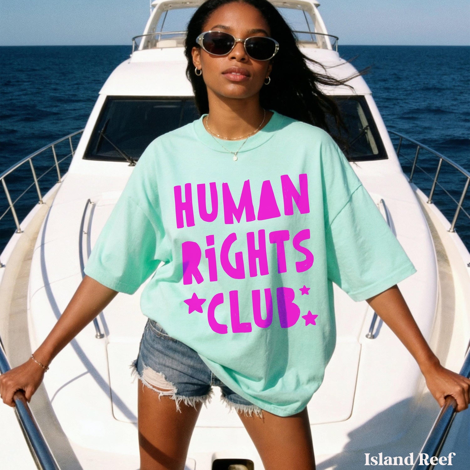 Woman in mint t-shirt with &amp;quot;Human Rights Club&amp;quot; text stands on a boat.