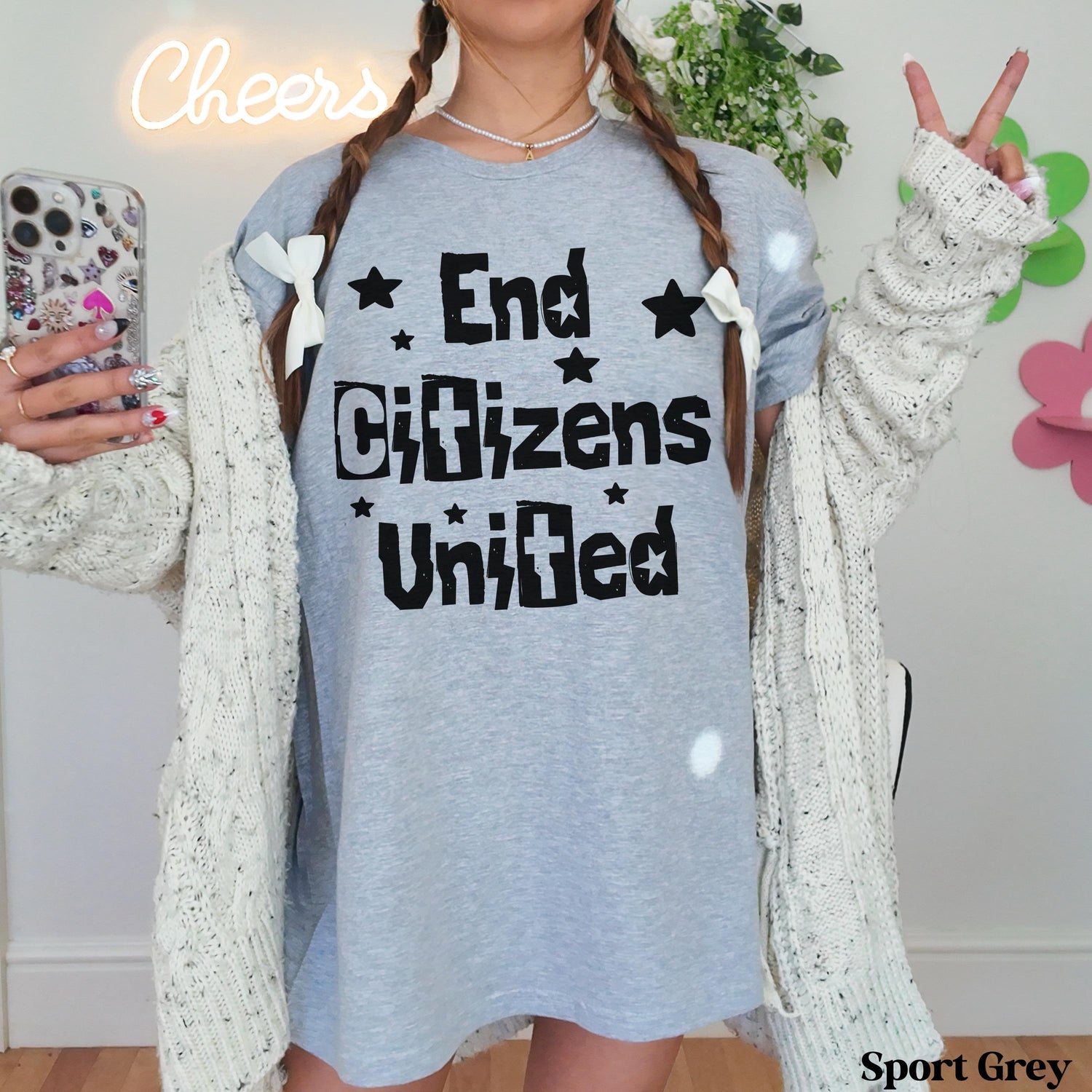 Woman wearing grey t-shirt with &amp;quot;End Citizens United&amp;quot; text and white ribbon bows in braids.