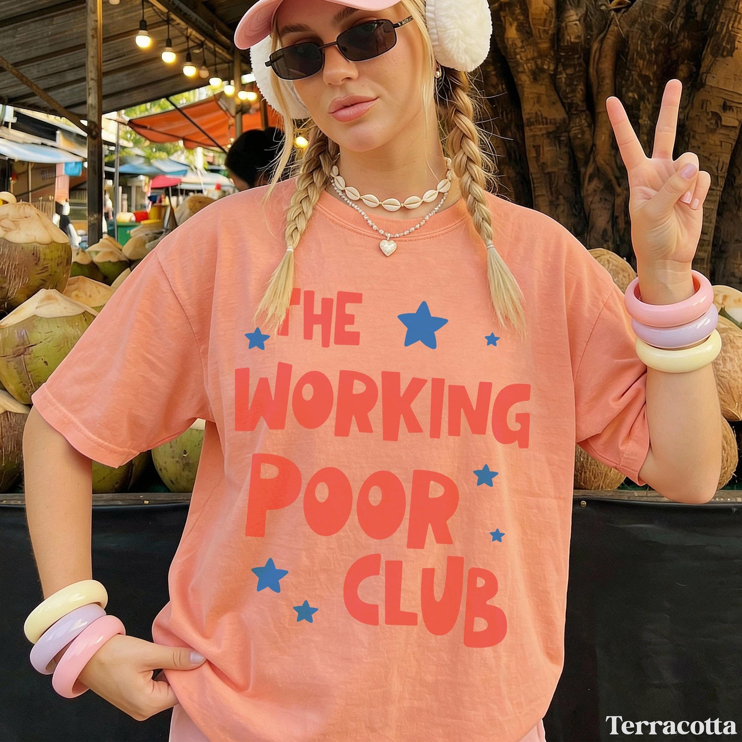 Woman wearing &amp;quot;The Working Poor Club&amp;quot; graphic tee, holding up peace sign.