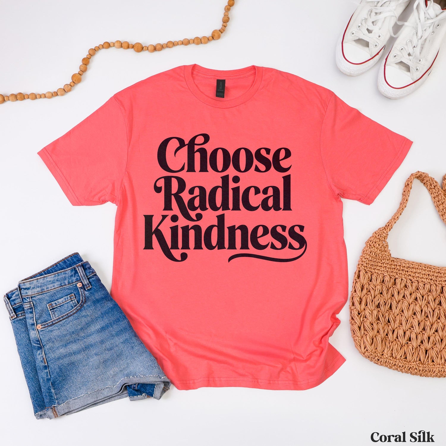 Coral silk t-shirt with &amp;quot;Choose Radical Kindness&amp;quot; text, styled with jeans and a straw bag.