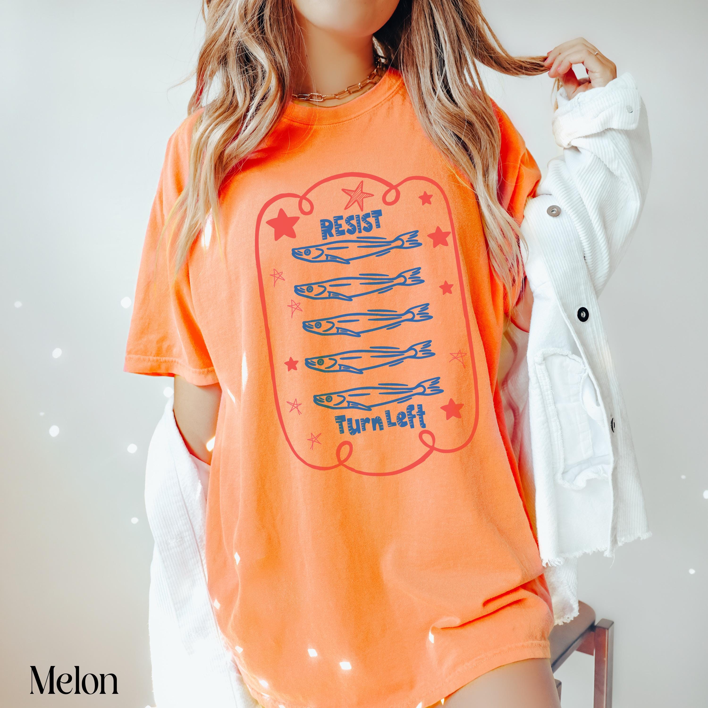 Orange t-shirt with &amp;quot;Resist Turn Left&amp;quot; text and five cartoon fish.