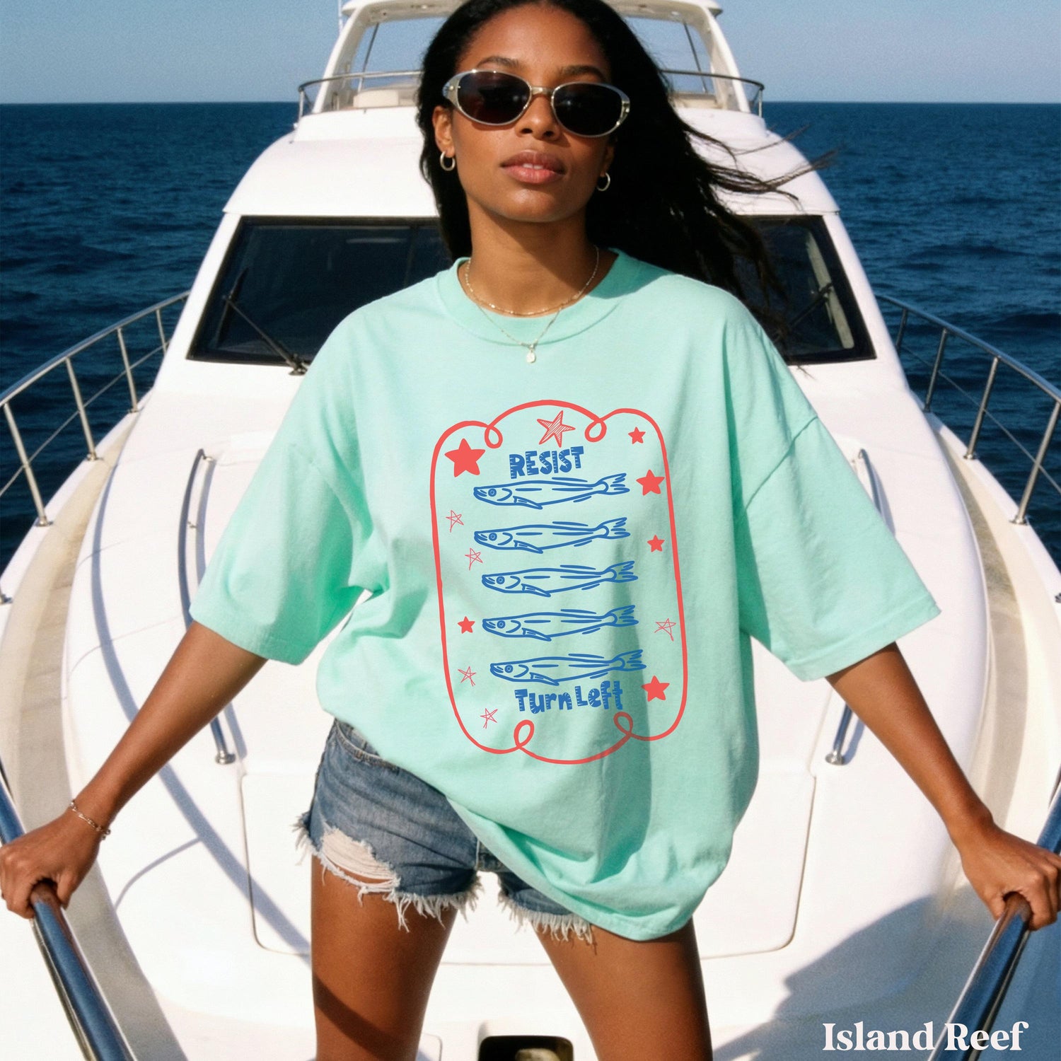 Woman in mint green t-shirt with fish graphic and text &amp;quot;Resist Turn Left&amp;quot; on a boat.
