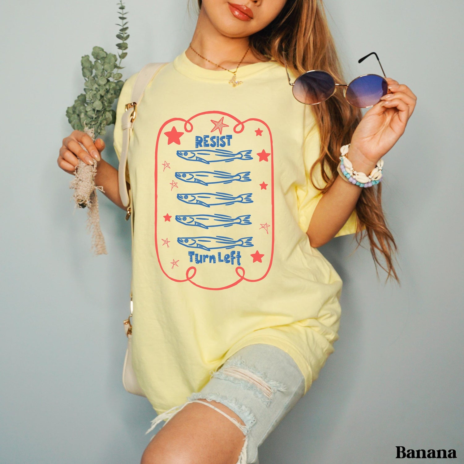 Pale yellow t-shirt with &amp;quot;RESIST&amp;quot; and &amp;quot;TURN LEFT&amp;quot; text and cartoon fish.