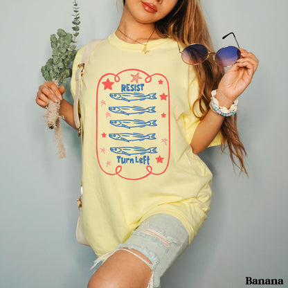 Pale yellow t-shirt with &amp;quot;RESIST&amp;quot; and &amp;quot;TURN LEFT&amp;quot; text and cartoon fish.