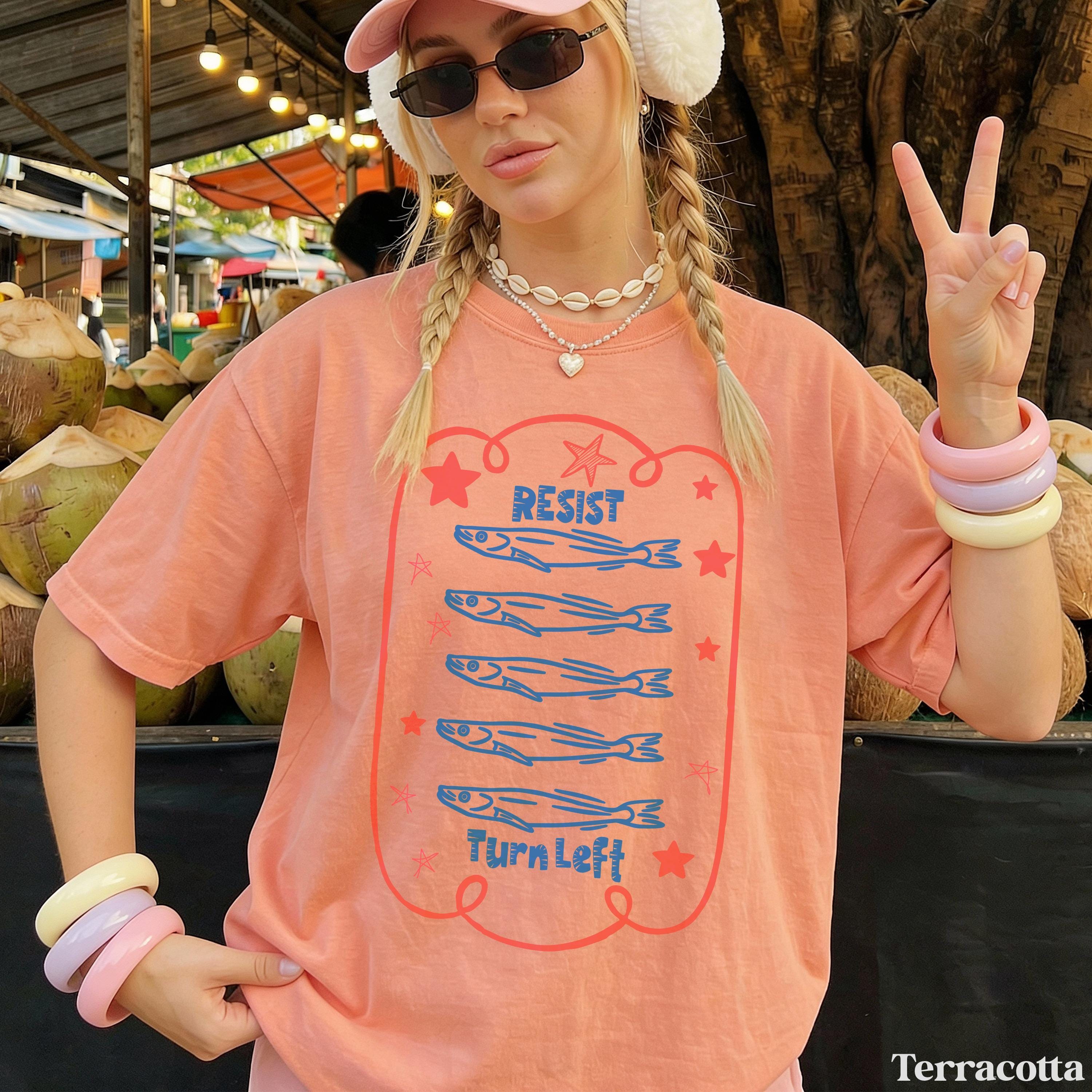 Salmon graphic with &amp;quot;Resist&amp;quot; and &amp;quot;Turn Left&amp;quot; text on a terracotta t-shirt.