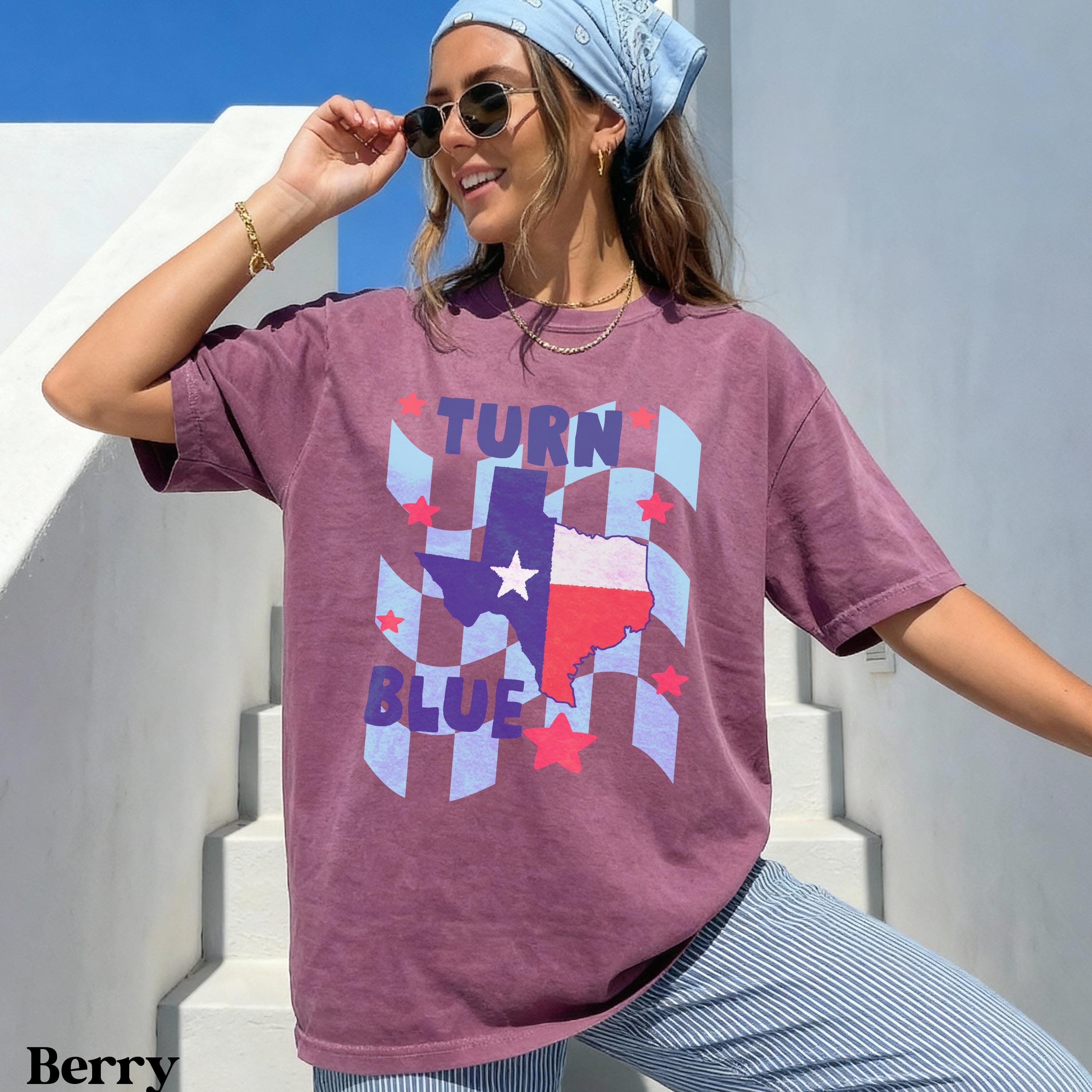 Woman wearing berry colored t-shirt with Texas flag and &amp;quot;TURN BLUE&amp;quot; text.