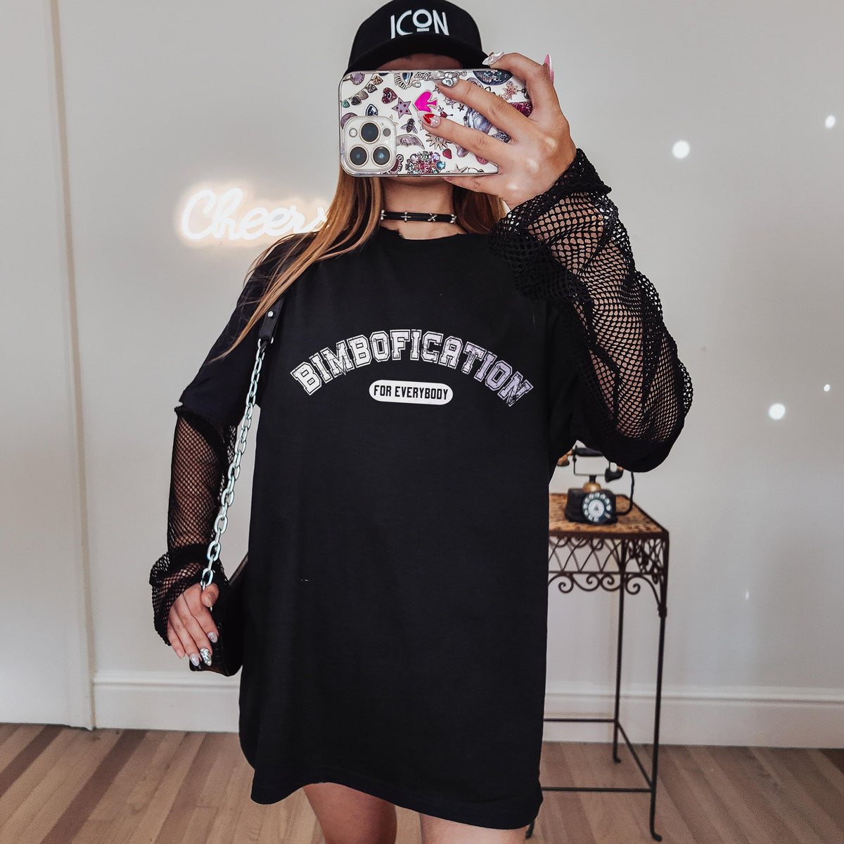 Woman wearing a black t-shirt with &amp;quot;DIMBOFICATION FOR EVERYBODY&amp;quot; text and mesh sleeves.