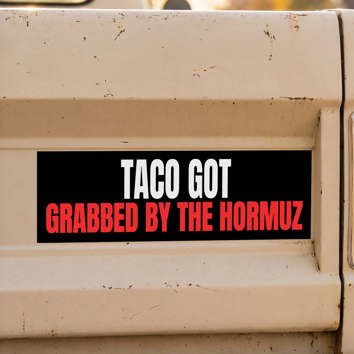 Black sticker on a tan surface reads &amp;quot;TACO GOT GRABBED BY THE HORMUZ&amp;quot;.